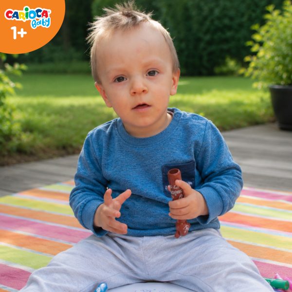 Roczne dziecko bawiące się pisakami Misiakami Carioca Baby siedzące na kocyku w ogrodzie.